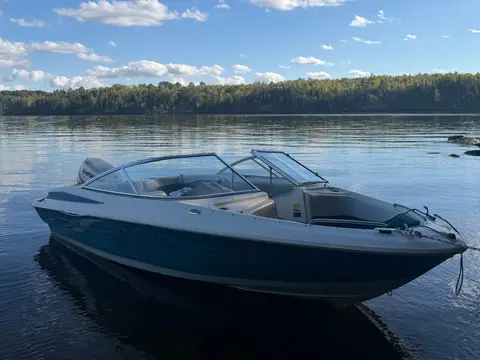 Russ's boat nosed up to shore on glassy water under a blue sky