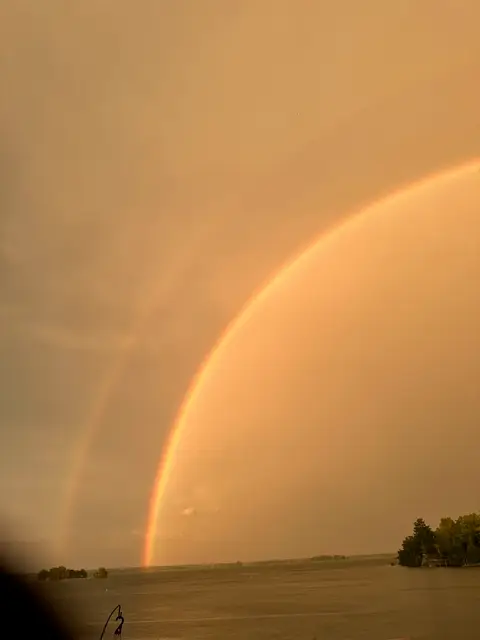 Double rainbow arcing over the lake at golden hour