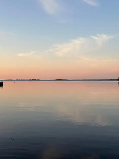 Glassy lake at dusk with a pastel sky reflected on still water