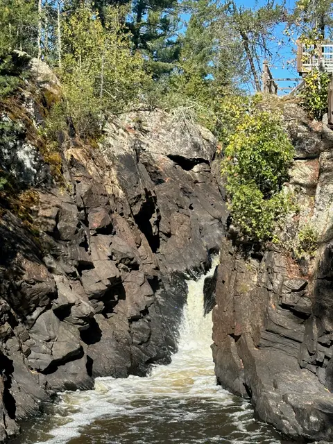 Waterfall dropping through a dark, narrow rock gorge