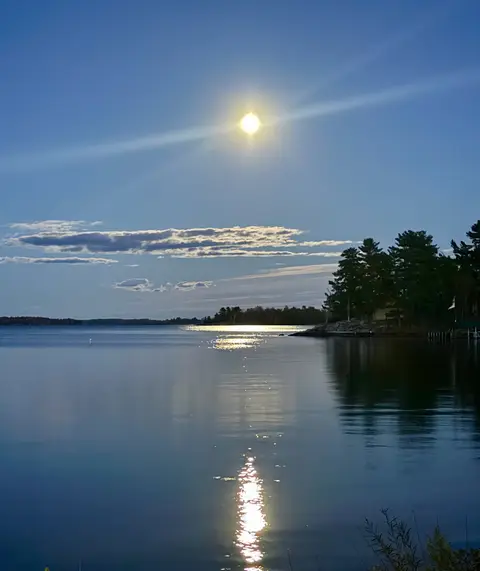 Full moon over a glassy lake with a long moonlight reflection