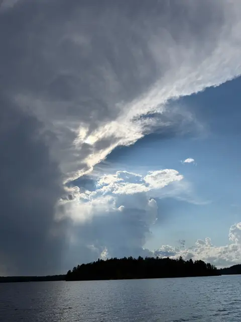 Towering storm clouds over the lake with an island silhouette